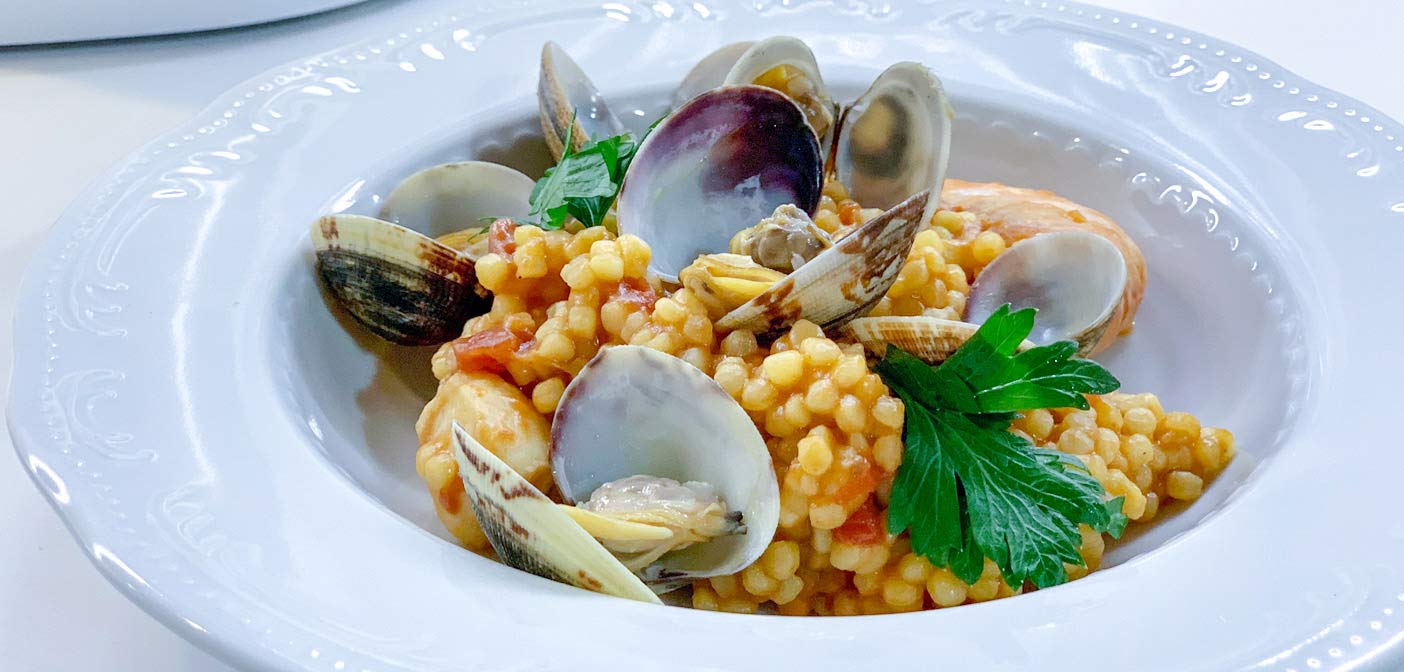 Tazza di fregula con zucca e molluschi in soffritto